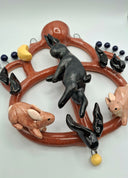 Decorative wall piece with ceramic animals on a circular brown flat vessel.