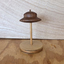 A small wooden UFO on a dowel attached to a round wooden base.