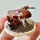 Sculpture of a orange and brown striped salamander standing on a wooden base and holding a kusarigama.