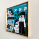 A framed square folk art style painting of a whimsical illustrated family scene. The artwork shows a man and child standing in front of a house, with another person sitting on the roof and white birds flying in the sky.