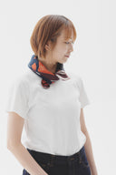 Person wearing a white shirt and dark pants with a colorful scarf around their neck on a white background