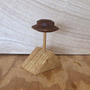 A small wooden display stand with a pyramid-shaped base, a vertical post, and a UFO photographed on a wood surface against a light wood wall.