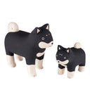 2 small wooden figurines of black and white shiba inu dogs, one is slightly smaller than the other.
