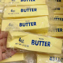 Multiple packages of 4oz salted butter squishy toys held by a hand.