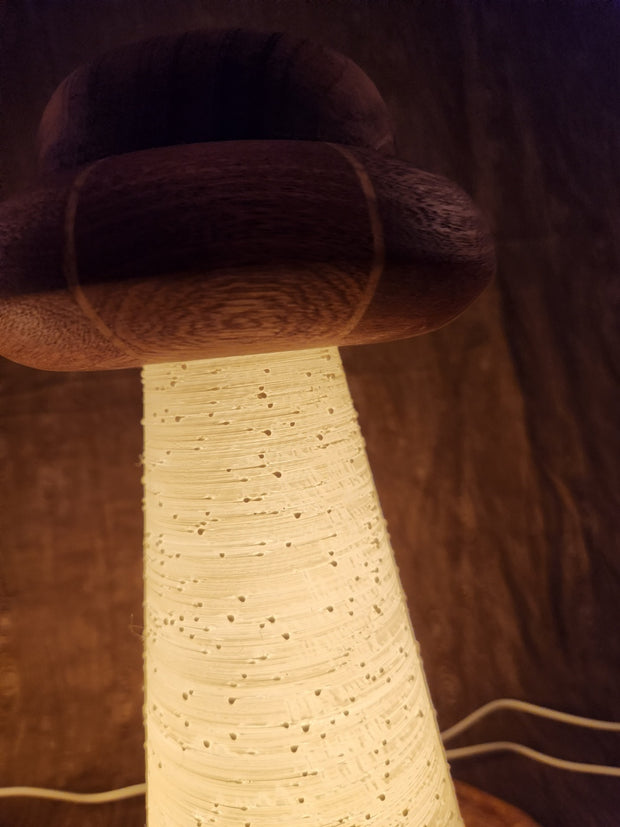 Wooden lamp with a simple UFO shaped top and a conical beam where light shines through, shown up close.