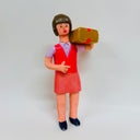 Clay sculpture of a female office worker, wearing a matching red and purple vest and skirt outfit and carrying a cardboard box over her shoulder.