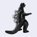 A black Godzilla toy figure with textured fur and silver-gray dorsal fins, shown in a walking pose against a light gray background.