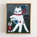 A framed folk art style painting of two white cats in winter clothing on a dark green background. The larger cat wears a red polka-dot scarf and holds a blue shopping back, while the smaller cat wears a red sweater.