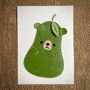 Flat vinyl fabric plush of a pear with the face of a bear and small clawed hands.