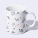 White ceramic mug with an all over pattern design of cartoon girl's heads with the day's of the week written on it. 