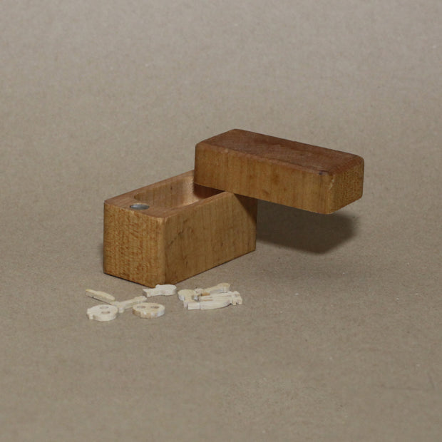 Wooden box with tiny wooden die cut items of weapons, and skulls. 