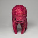 A handmade felted wool animal figurine in a vibrant magenta-pink color, standing on a neutral light gray background.
