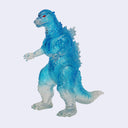 A translucent blue and white Godzilla toy figure with red eyes, standing on a light gray background.