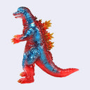 A translucent plastic toy figure of a Godzilla-like dinosaur, featuring a metallic blue upper body and red lower body, with yellow and orange spines and claws, set against a plain light gray background.