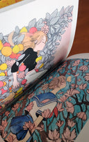 Close up of a book interior, with 2 full bleed pages of illustrations of stylized characters in nature fantasy settings.