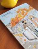 Illustration book titled 'Panakid' on a wooden surface with a yellow object in the corner.