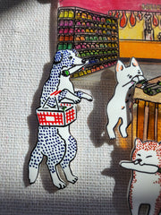 Shadowbox assembling of small sculptural pieces. Small dogs walk around a supermarket, pushing carts or holding baskets. Gold beads and strings decorate the piece.