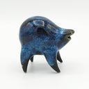 Black and blue ceramic sculpture of a rounded body quadruped creature with an open mouth goofy smile. It has small golden eyes and a swirling texture on its body.