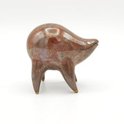 Orangish brown ceramic sculpture of a rounded body quadruped creature with an open mouth goofy smile. It has small golden eyes and an oil slick texture on its body.