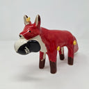 Ceramic sculpture of a red fox with a large fluffy tail and black paws. It holds a cap in its mouth, white and black with a Big Boss Robot logo on it. Small yellow flames come off of the fox's body.