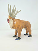 Ceramic sculpture of a deer character, with a painted red face, fluffy white beard and many, many ivory colored antlers coming out of its head. It has bird-like feet with talons.