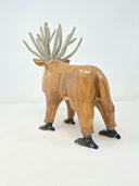 Ceramic sculpture of a deer character, with a painted red face, fluffy white beard and many, many ivory colored antlers coming out of its head. It has bird-like feet with talons.