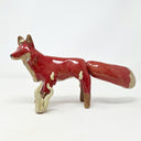 Glossy ceramic sculpture of a red fantasy style fox with a very fluffy tail and cream colored flames coming off its front paw and spreading slowly onto its body.