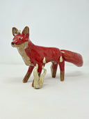 Glossy ceramic sculpture of a red fantasy style fox with a very fluffy tail and cream colored flames coming off its front paw and spreading slowly onto its body.