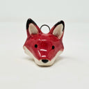 Ceramic charm of a red fox's head with black ears and white chin and inner ears. It is attached to a wire hook.