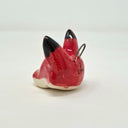 Ceramic charm of a red fox's head with black ears and white chin and inner ears. It is attached to a wire hook.