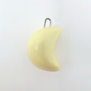 Light yellow sculpture shaped like a crescent moon, attached to a hook.