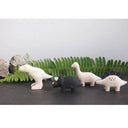 Set of small dinosaur figurines on a gray surface with green leaves in the background