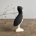 Decorative figure of a shoebill bird, standing on a wooden surface with a gray background