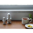 Two wooden polar bear figures - both standing on their hind legs, one is a parent and the other is the child. They are on a table with tea and cookies.