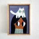 A framed folk art painting featuring a stylized girl with black hair, a green-and-white striped shirt, and a white cat on their head, set against a muted purple background. Both the girl and the cat smoke a cigarette. The light wood frame hangs on a white wall.