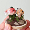 Small sculpture of 2 ranchu goldfish on a wooden base with paper plants.