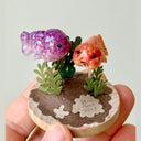 Decorative item with two small fish figurines on a circular base with plants and a date.