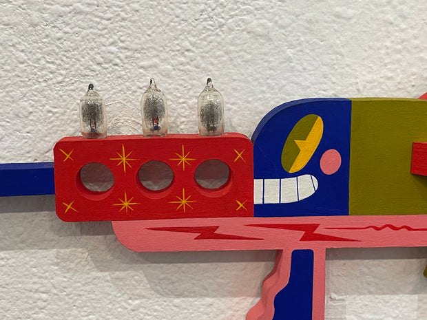 Colorful abstract sculpture with geometric shapes and light bulb-like objects on a textured wall.