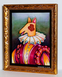 A framed whimsical painting of a dog dressed in a ruffled white collar and a pink, orange, and yellow striped outfit, set in an ornate gold frame against a light gray wall.