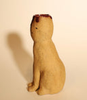 Ceramic sculpture of a tall brown cat, sitting and looking forward with simplistic eyes and a nose. Its head is cut open in a cross section, with blood spilling out.