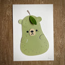 Flat vinyl fabric plush of a pear with the face of a bear and small clawed hands.