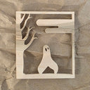 Laser cut design into wood of a ghost like creature with 2 legs walking amongst barren trees and clouds.