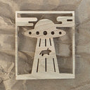 Laser cut design into wood of a cow being lifted up by a UFO.