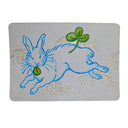 Illustration of a blue rabbit on gray paper jumping with a clover nearby.