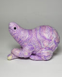 A small handcrafted felted wool animal figurine in a crouched pose, featuring a marbled purple and white color pattern with a small black bead eye, set against a plain light gray background.
