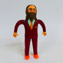 Clay sculpture of a man in a burgundy business suit, standing with his arms slightly out at both sides. He has a long brown beard and matching long hair.
