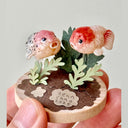 Small decorative piece with goldfish and plants on a circular base held by a hand.