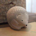 White wooden hedgehog figurine on a wood background.