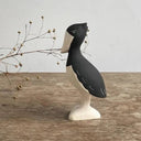 Decorative figure of a shoebill bird, standing on a wooden surface with a gray background