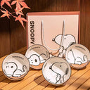 Set of 4 bowls with graphics of Snoopy, sitting or laying. They are with a brownish pink gift box set.